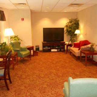 A cozy living room with multiple seating options, a large television, and warm lighting from lamps.