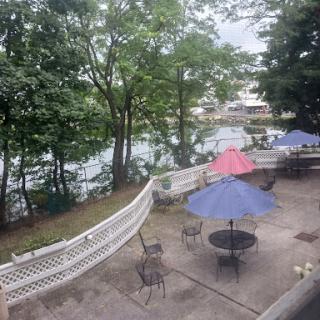 A serene outdoor patio area by the water, featuring colorful umbrellas and surrounded by lush trees.