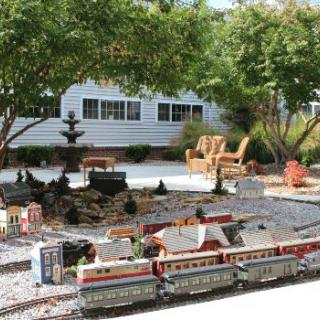 A miniature train set displayed in a landscaped garden setting.
