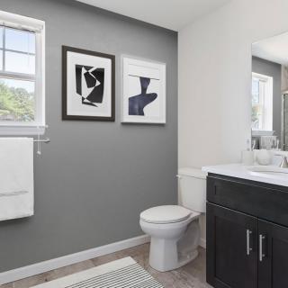 A modern bathroom featuring a toilet, sink with cabinet, and abstract wall art.