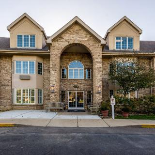 A two-story building with a stone facade and multiple windows, featuring a central entrance.