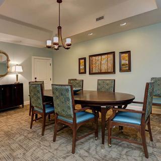 A well-decorated dining room featuring a round table, upholstered chairs, and elegant lighting.