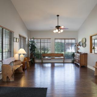 A spacious living room filled with natural light, featuring wooden floors and cozy furniture.