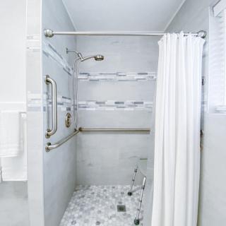 A modern bathroom shower area with marble flooring and grab bars.