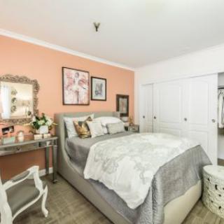A cozy bedroom with pastel walls, decorative artwork, and elegant furnishings.