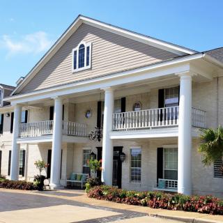 A large residential house featuring classic architecture with prominent columns and a balcony.
