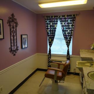 A cozy salon interior featuring pink walls, elegant curtains, and stylish furniture.