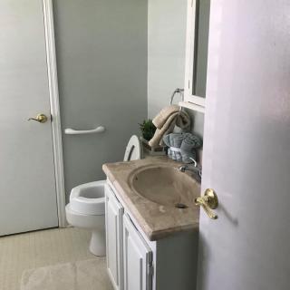 A clean, compact bathroom with a sink, toilet, mirror, and neatly arranged towels.