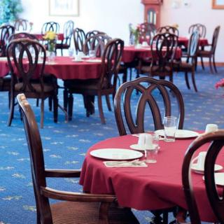 An empty restaurant dining area with neatly arranged tables and chairs, adorned with red tablecloths.