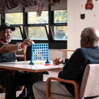 Two people playing a game of Connect Four indoors.