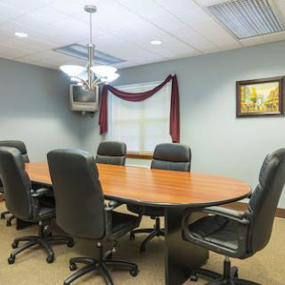 A conference room with a large oval table and several leather chairs.