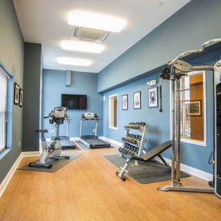 A small gym with various exercise equipment, including treadmills, a stationary bike, and a weight bench.