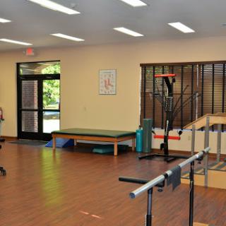 A well-lit physical therapy room equipped with exercise tools and a comfortable waiting area.