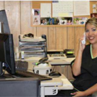 A woman sitting at her desk in an office while talking on the phone.