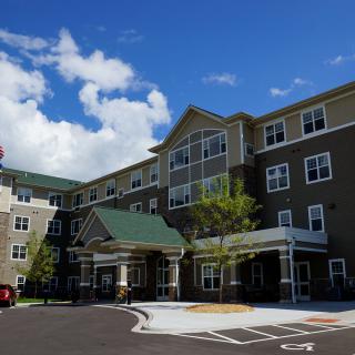 A multi-story residential building with a green roof and clear blue sky.