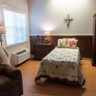 A cozy bedroom with a single bed, nightstand, and a lamp by the window.