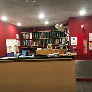 A cozy office reception area with a red wall and neatly organized bookshelves.