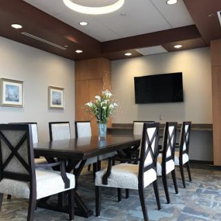 A modern conference room with a large table, comfortable chairs, and a decorative flower arrangement.