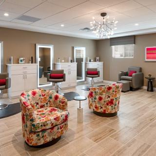 A chic and modern salon interior with floral chairs and elegant lighting.