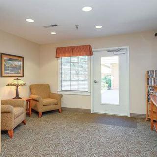 A cozy waiting area with chairs, a lamp, and artwork on the walls.