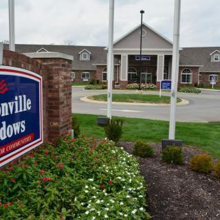 A landscaped entrance to a building with a prominent sign and flags.