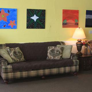A cozy living room with a plaid sofa, decorative pillows, and colorful artwork on the wall.