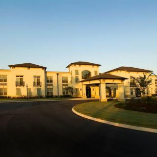 A large, modern residential building with well-maintained landscaping and a paved driveway during daytime.