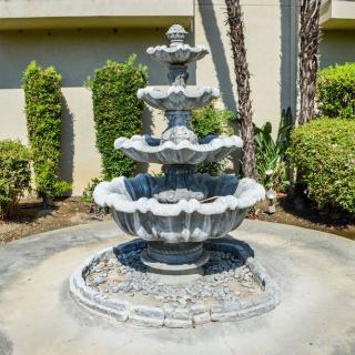 A decorative three-tiered stone fountain in a garden setting.