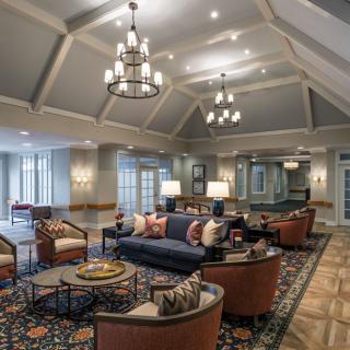 A spacious and elegantly designed living room with comfortable seating, decorative chandeliers, and a warm ambiance.