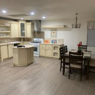 A modern kitchen and dining area with an open layout, featuring a central island and wood flooring.