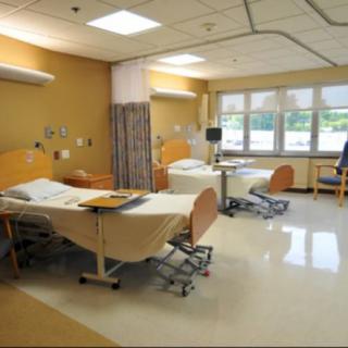 A clean and modern hospital room with two beds and medical equipment.