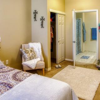 A cozy bedroom with a chair, closet, and an adjoining shower area.