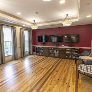 A stylish living room featuring hardwood flooring, modern furnishings, and flat-screen televisions.