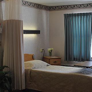 A serene hospital room featuring a neatly made bed, soft lighting, and inviting curtains.