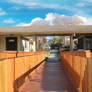 A wooden walkway leading to an outdoor space under a clear blue sky.
