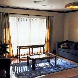 A cozy living room with a sofa, coffee table, and a large window allowing natural light.