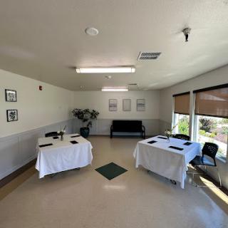 A bright and spacious interior featuring two tables, chairs, and decorative elements, creating a welcoming atmosphere.