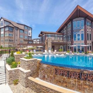 A modern apartment complex featuring a large outdoor swimming pool surrounded by elegant architecture.