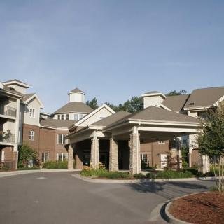 A residential building with a prominent entrance and surrounding greenery.