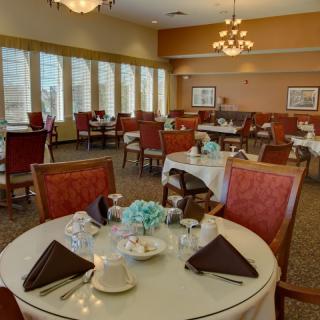 Elegantly set dining tables in a restaurant with large windows and warm lighting.