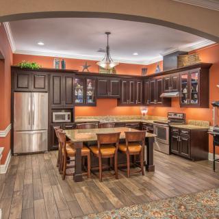 Modern kitchen with dark wood cabinets and stainless steel appliances, featuring an island counter and bar stools.