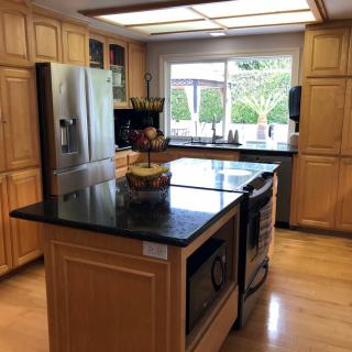 A modern kitchen featuring a large island with granite countertops and stainless steel appliances.