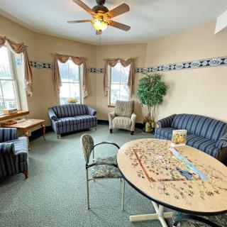 A cozy living area featuring comfortable sofas, a game table, and ample natural light.