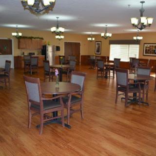 A spacious dining area featuring wooden tables and chairs, illuminated by multiple light fixtures.