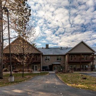 A large building with a driveway set against a backdrop of cloudy skies and surrounded by trees.