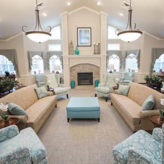 A spacious and elegantly designed living room featuring symmetrical sofas, a central ottoman, and a fireplace with surrounding decor.