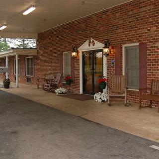 A brick building entrance with rocking chairs and potted plants on the porch.