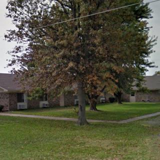 A quiet suburban street featuring homes and a large tree.