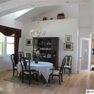 A cozy dining room with a table and chairs, elegant chandelier, and decorative furnishings.