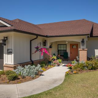 A charming single-story house with a welcoming front yard and colorful flowers.